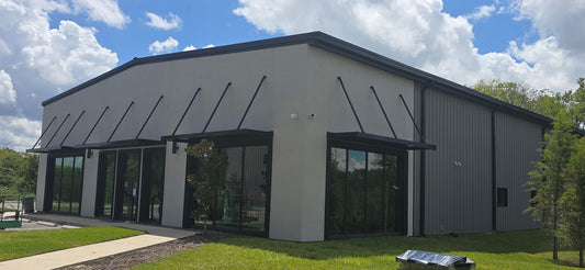 Commercial office building with black flat metal awnings on hanger rods over storefront glass