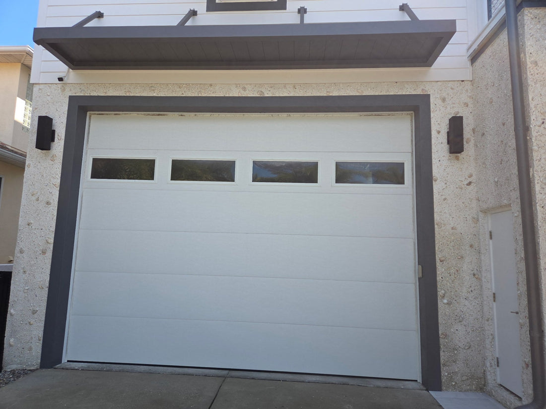 Gray aluminum garage door awning with rod-supported brackets over a white garage door on a shell-stone home in Tampa, Florida