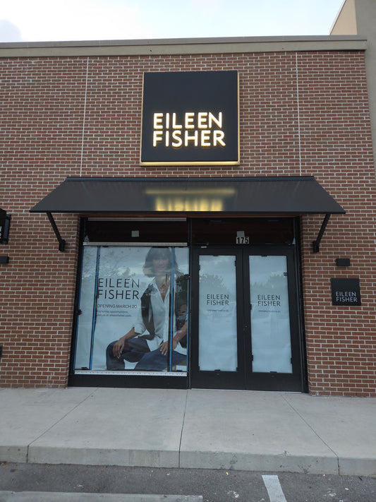 Black metal storefront awning over a retail entrance on a brick shopping center facade