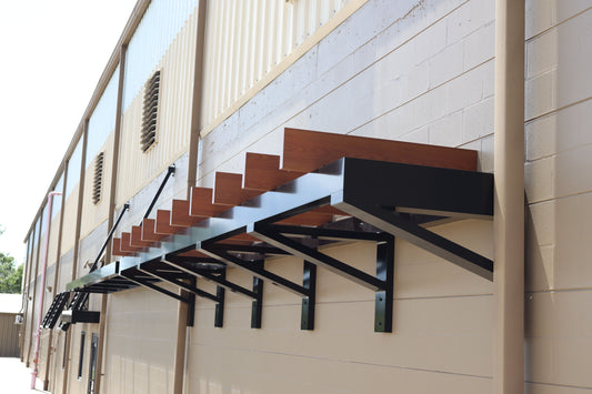 Woodgrain aluminum louvered metal awning on a commercial building with black cantilever brackets