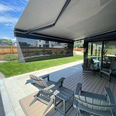 Outdoor patio with retractable awning, chairs, and a view of a residential area.