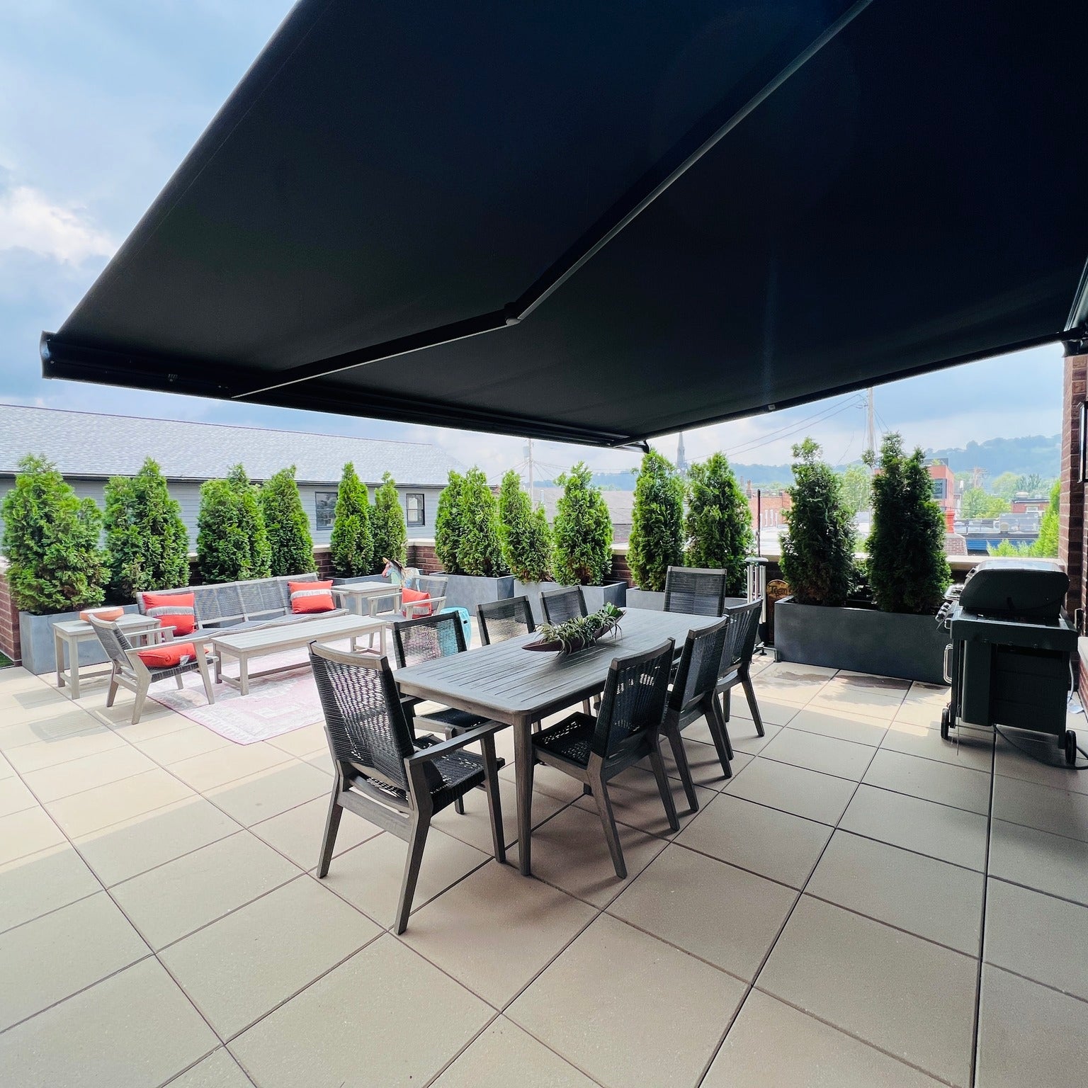 Outdoor patio with dining table, chairs, and black retractable awning on a sunny day.